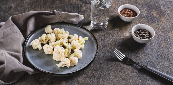 Pieces of raw cauliflower for diet on a plate on the table web banner photo