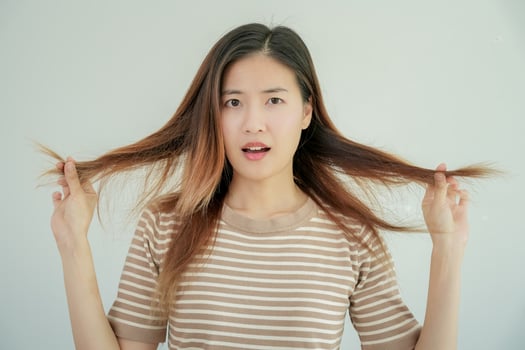 Asian woman very sad and upset looking at damaged hair, hair loss, hair thinning problem, vitamin deficiency, baldness, postpartum, biotin, zinc, menstrual or endocrine disorders, hormonal imbalance photo