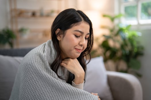 Young woman with pharyngitis feeling unwell sore throat, wrapped in blanket on sofa, Concept of feeling sick and healthcare photo