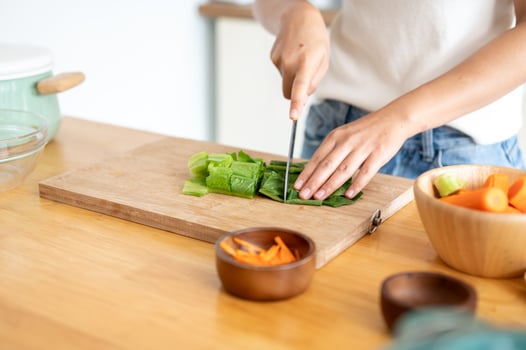 A close-up image of a woman cutting lettuces on a cutting board, cooking in the kitchen. photo