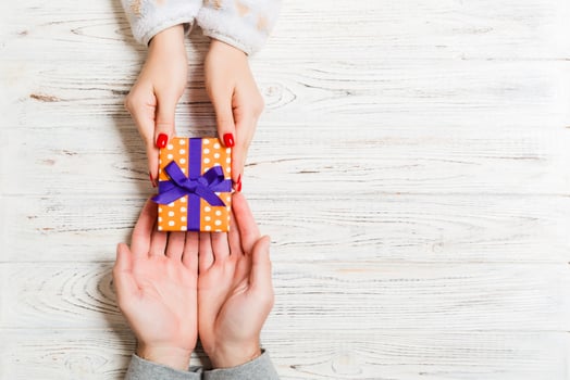 Top view of a gift in male and female hands on wooden background. Congratulation of each other concept. Copy space photo