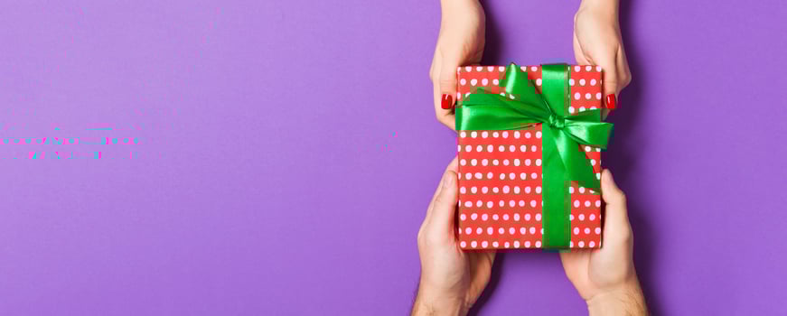 Top view of two people sharing a present on colorful background. Holiday and surprise concept. Copy space photo