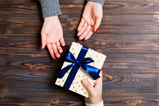 Top view of a woman and a man giving and receiving a present on wooden background. Love and relationship concept. Close up photo