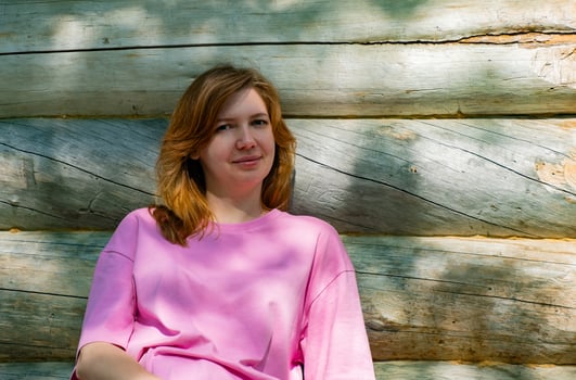 Woman Sitting by Rustic Cabin in Sunny Forest photo