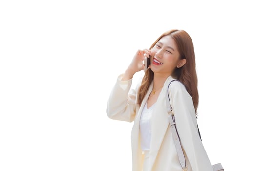 Young Asian business woman in white suit smiles and holds talk smartphone in her hands in happily workday awhile isolated on white background. photo