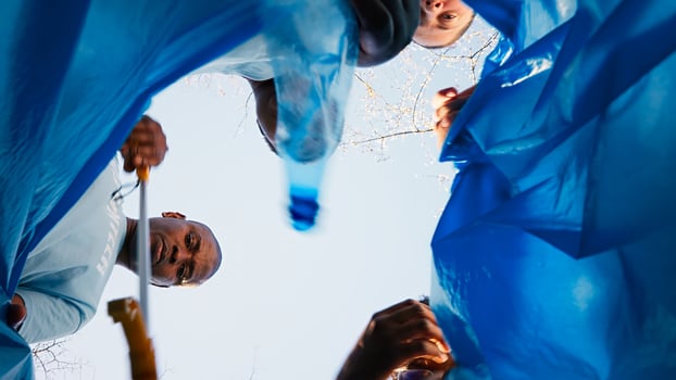POV of environmental activists clearing the woods sorting recyclables in a disposal, collecting waste an plastic trash in a garbage bag. Individuals support ecological movement. Camera A. photo