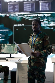Navy operations specialist reading new mission case files in command center, working with satellite real time data projection on a big screen. Soldier enlisted in national army defense program. photo