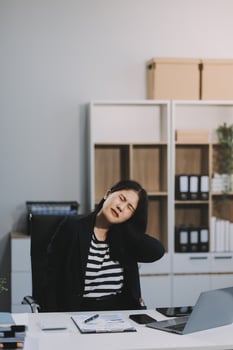 Office asian business woman stretching body for relaxing while working with laptop computer at her desk, office lifestyle, business situation photo