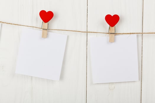 white pieces of paper on clothespins with a heart on a wooden background photo