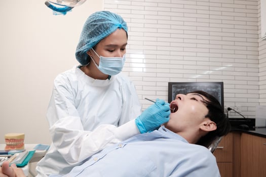 Asian female dentist examine young male patient teeth and toothache stomatology in dental clinic, well-being hygiene checks, and professional orthodontic healthcare work in doctor's office hospital. photo