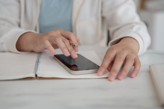 A close-up image of a woman in casual clothes is using her smartphone while working. photo