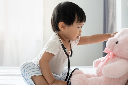 Young cute Asian girl Playing doctor with favorite toys. Sitting on the bed. little girl having fun. take care teddy bear Playing alone in the bedroom, future, dream, development, EF , IQ, EQ photo