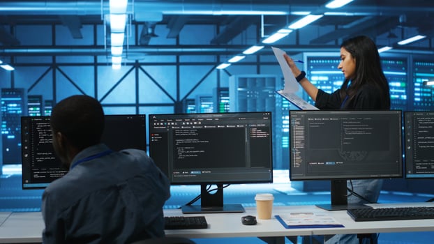 Indian manager in data center doing inspection on electronics and workers, ensuring order. Team leader reading clipboard files, supervising employees in server room infrastructure components photo