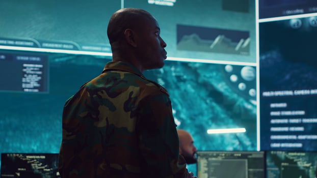General of the army overseeing special reconnaissance mission in control center, undertake intelligence gathering operations with CCTV footage and a world map on a big screen. Camera A. photo