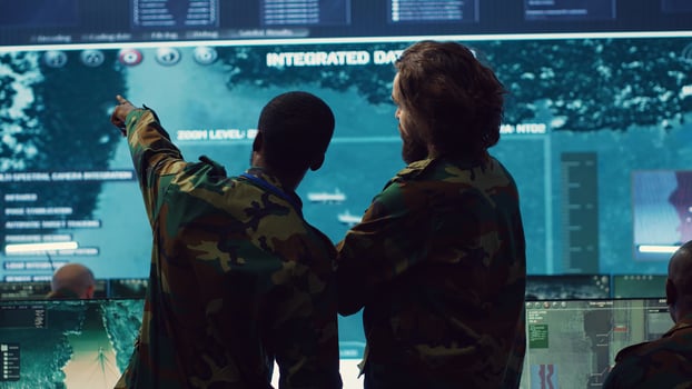 Diverse team of military personnel examining gathered information from CCTV satellite footage, transmitting crucial data to field troops. Army officers work on defense in command center. Camera A. photo