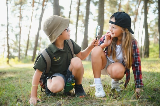 Two happy children having fun during forest hike on beautiful day in pine forest. Cute boy scout with binoculars during hiking in summer forest. Concepts of adventure, scouting and hiking tourism photo