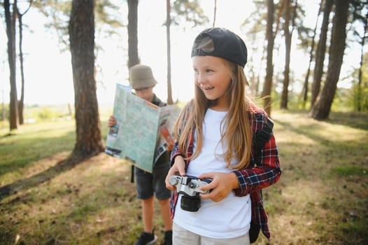 Group of curious happy school kids in casual clothes with backpacks exploring nature and forest together on sunny autumn day. photo