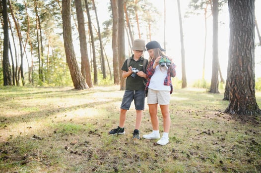 Happy excited school children with backpacks in casual clothes enjoying walk in forest on sunny autumn day, two active kids boy and girl running and playing together during camping trip in nature. photo