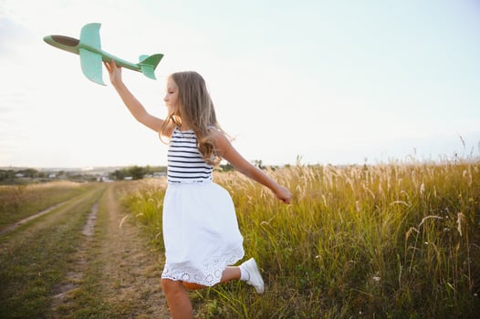 Happy girl runs with a toy airplane on a field in the sunset light. children play toy airplane. teenager dreams of flying and becoming a pilot. girl wants to become a pilot and astronaut. Slow motion. photo