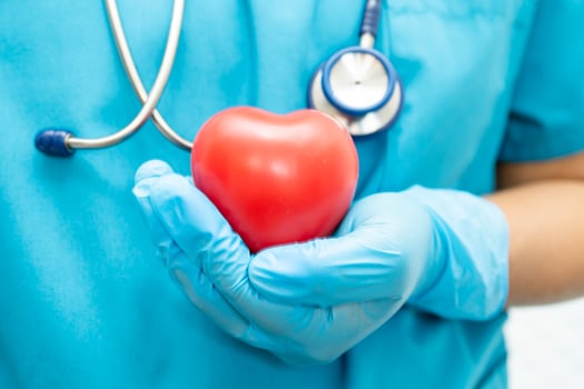 Doctor holding a red heart in hospital ward, healthy strong medical concept. photo