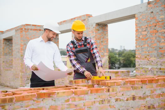 engineer and builder in hard hats discussing blueprint on construction site. photo