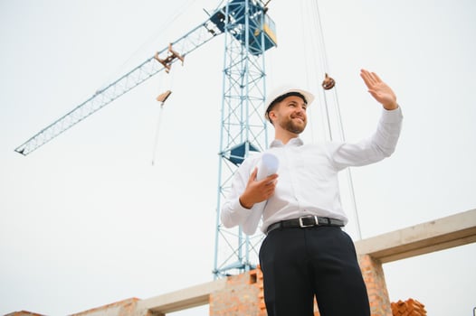 Construction engineer supervising progress of construction project stand on new concrete floor top roof and crane background. photo