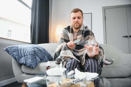 A sick man sits at home on a gray sofa with a blanket. Illness, protection, coronavirus, illness, flu photo