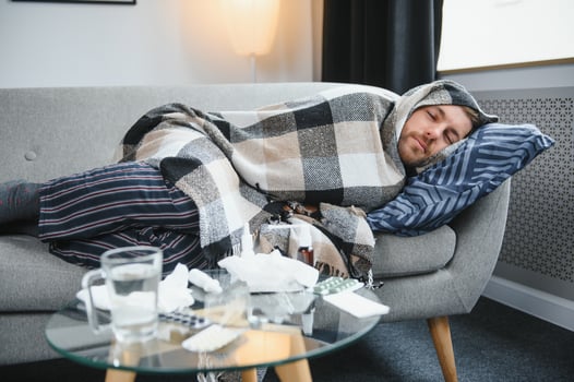 A sick man sits at home on a gray sofa with a blanket. Illness, protection, coronavirus, illness, flu photo