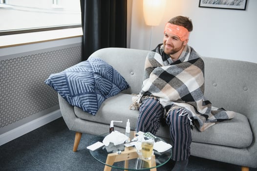 A sick man sits at home on a gray sofa with a blanket. Illness, protection, coronavirus, illness, flu photo