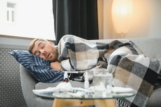 It's cold at home in wintertime. Man freezing in his house in winter because of broken thermostat. young guy wrapped in woolen plaid shivering while sitting on sofa in living room interior photo