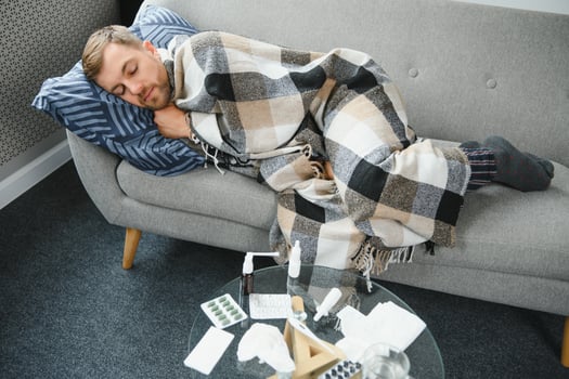 It's cold at home in wintertime. Man freezing in his house in winter because of broken thermostat. young guy wrapped in woolen plaid shivering while sitting on sofa in living room interior photo