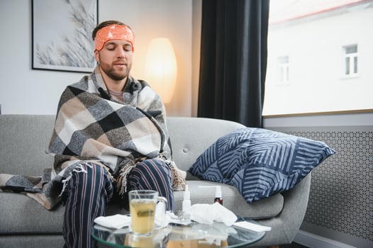 A sick man sits at home on a gray sofa with a blanket. Illness, protection, coronavirus, illness, flu photo