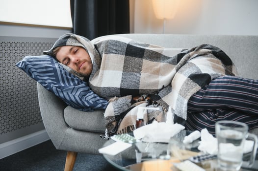 It's cold at home in wintertime. Man freezing in his house in winter because of broken thermostat. young guy wrapped in woolen plaid shivering while sitting on sofa in living room interior photo