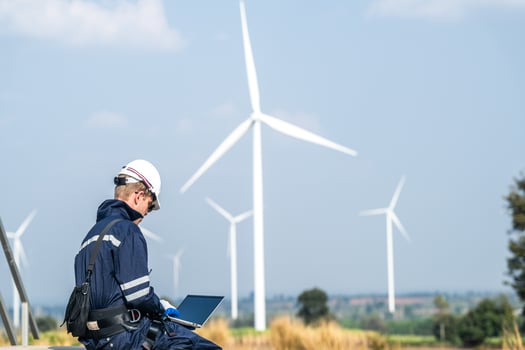 A wind energy technician with a laptop analyzes the efficiency of turbines on a clear day. photo