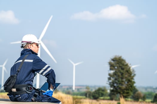 A wind energy technician with a laptop analyzes the efficiency of turbines on a clear day. photo