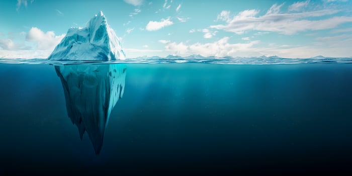 Iceberg concept, an iceberg floating in the ocean with half of it visible above and one big part under water. Blue sky background with copy space for text. Conceptual illustration about global warming photo