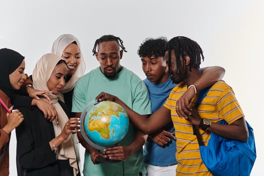 A diverse group of students is gathered around a globe, engrossed in exploration and study, their vibrant energy captured against a pristine white background, symbolizing unity and curiosity in their photo