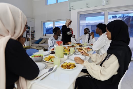 In the sacred month of Ramadan, a Muslim family joyously comes together around a table, eagerly awaiting the communal iftar, engaging in the preparation of a shared meal, and uniting in anticipation photo