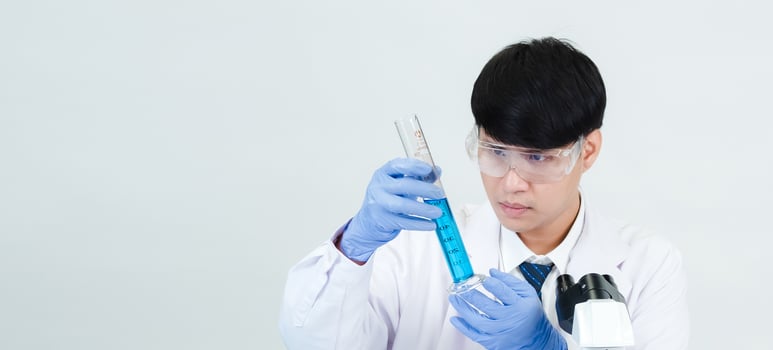 Portrait asian man student scientist wearing a doctor gown in the lab looking hand at chemist. caused by mixing reagents in scientific research laboratories with test tubes and microscope on the table photo