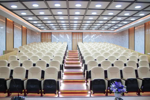 Rows of cream-colored chairs in an empty auditorium photo
