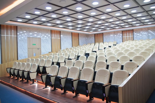 Rows of cream-colored chairs in an empty auditorium photo