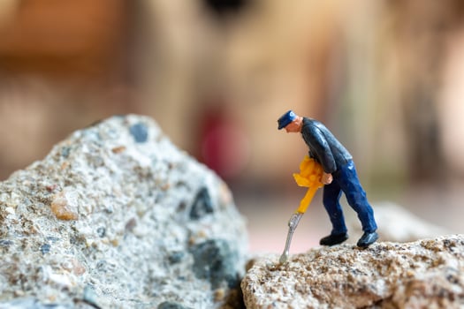 A miniature worker worker drilling a big rock . Themes of perseverance, strength and labor. photo