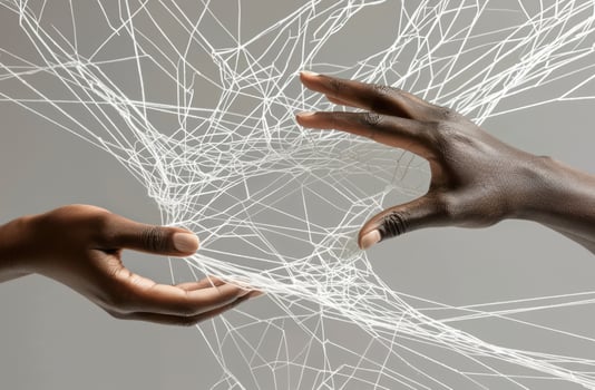 Photo shows hands weaving strings together, forming an intricate web. Metaphor of various connections between people through communication, help, love, care