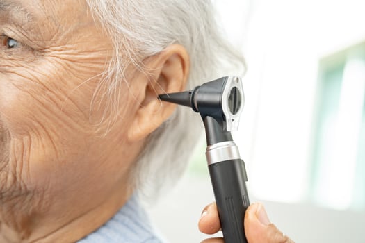 Audiologist or ENT doctor use otoscope checking ear of asian senior woman patient treating hearing loss problem. photo