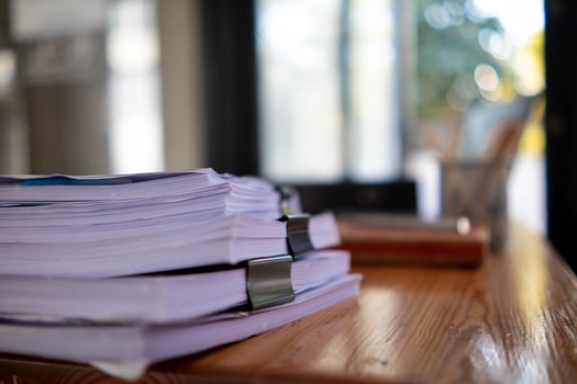 pile of documents sat on desk in office was pile of documents that had been prepared to be presented at meeting as summary of annual operations. Documents prepared for storage and piled on the desk. photo