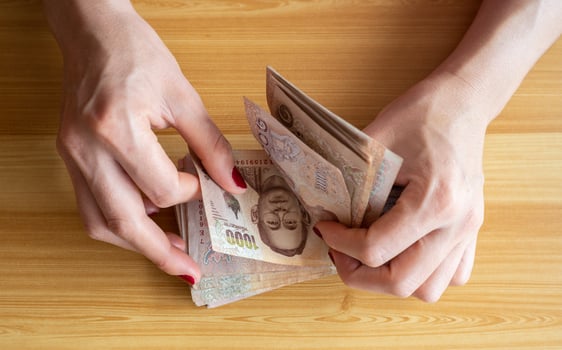 High angle view of an accountant woman with red fingernails holding and counting Thai baht banknotes. The baht is the official currency of Thailand. photo