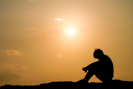 A silhouette of a man sitting on a hill photo