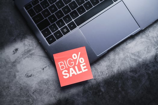 Laptop with a red adhesive note with big sale on it. Discounts, online shopping. Desktop view with copy space. photo