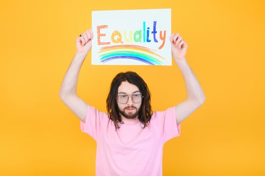 gay man with a gay pride flag smiling and looking away on yellow background. photo