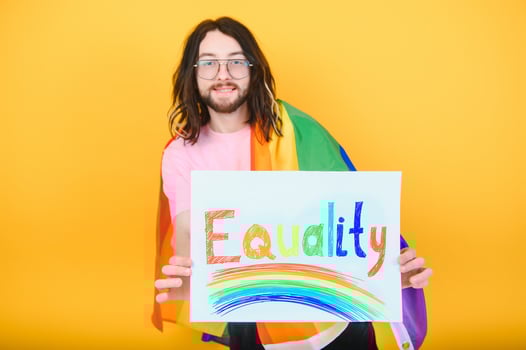 Handsome young man with pride movement LGBT Rainbow flag on shoulder against white background. Man with a gay pride flag. photo